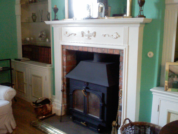 A Balmoral urn (PN851) and a pair of Rococo leaf wings (PN664) have been used to great effect above this wood burning stove. Painted white, they emphasise the traditional design of this living room.